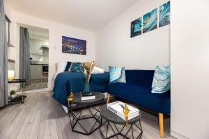 een woonkamer met een blauwe bank en een bed bij Cozy Ground-Floor Studio, Excellent City Access in Londen