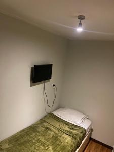 um quarto com uma cama e uma televisão de ecrã plano na parede em Hostal low cost em Santiago