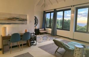 a living room with chairs and a table and windows at Lux Villa w/ Stunning Panoramic Ocean Views in Bequia