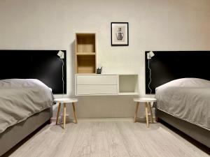 a bedroom with two beds and two tables and shelves at Simple room in Trondheim