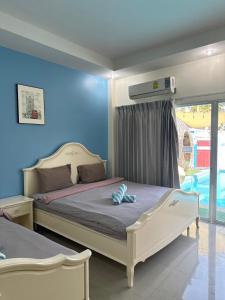 een slaapkamer met 2 bedden en een blauwe muur bij Unique Pool Villa Resort in Map Fak Thaung