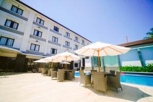 a row of tables with umbrellas in front of a hotel at Sahid T-More Hotel in Kupang