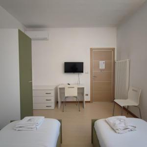 Zimmer mit 2 Betten, einem Schreibtisch und einem TV in der Unterkunft B&B Casa Lilla in Verzuolo