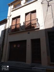 - un bâtiment blanc avec un balcon et deux portes dans l'établissement Dortoirs Hommes, à Béziers