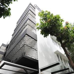 a tall white building with a tree in front of it at Family Inn - Airport Hotel in Dhaka