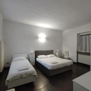 2 łóżka w pokoju z białymi ścianami w obiekcie B&B Casa Lilla w mieście Verzuolo