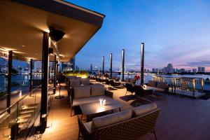 a rooftop deck with tables and chairs on a building at Ten Six Hundred, Chao Phraya, Bangkok by Preference, managed by The Ascott Limited in Bangkok