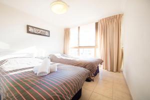 2 camas individuales en una habitación con ventana en Warringa Surf Holiday Apartments, en Gold Coast