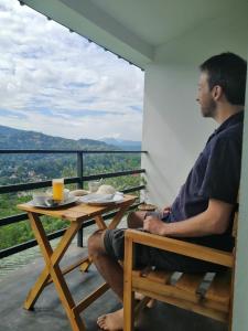 康提的住宿－Glenview hotel & homestay，坐在阳台上桌子上的男人