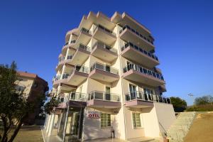 een hoog wit gebouw met balkons erop bij Dort Mevsim Suit Hotel in Canakkale