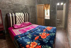 un letto con un piumone colorato in una camera di bungalow karohill a Berastagi