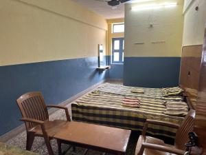 a room with a bed and two chairs and a table at Navata Lodge in Pulivendla