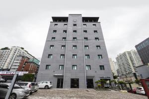 un grand bâtiment gris avec des voitures garées dans un parking dans l'établissement Browndot Suwon cityhall, à Suwon