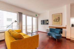 un salon avec un canapé jaune et un fauteuil bleu dans l'établissement SeaView with style, à Ostende