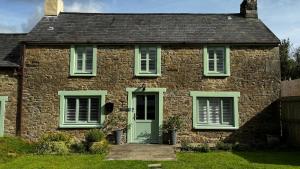 uma antiga casa de pedra com uma porta verde em Spacious 4 Bedroom Farmhouse em Pembrokeshire
