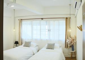 Dos camas en una habitación con ventana. en Private Full-Floor Spacious 5BR in China Town, en Bangkok