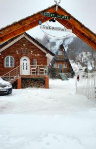 una casa en la nieve con un cartel para un hostal en Vilat Pllumaj, en Gropat e Selcës