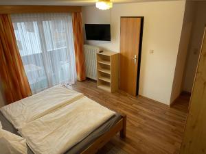 ein Schlafzimmer mit einem Bett, einer Kommode und einem TV in der Unterkunft Haus Grünstein in Biberwier