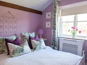 a bedroom with a bed with purple walls and a window at The Hayloft- Dws in Marshwood