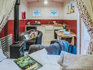 a living room with a stove and a kitchen at Goosewing Hut-qu7072 in Melton Constable