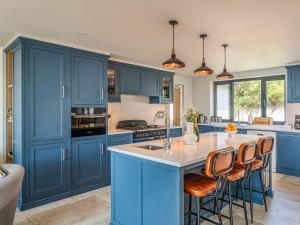 a kitchen with blue cabinets and a island with bar stools at Blue Seas in Mawgan Porth