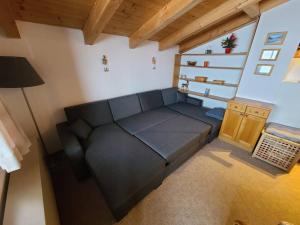 una sala de estar con un sofá negro en una habitación en Zillertal-Arena 42m2 (2-6 persons: 2adults +4kids), en Krimml