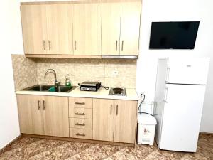 een keuken met houten kasten, een wastafel en een koelkast bij Hajdini Apartament in Sarandë