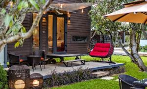 a tiny house with a red chair on a deck at Glamp Wilderness in Nelamangala