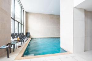 - une piscine dans un bâtiment avec des chaises et une table dans l'établissement Prachtig appartement met zwembad en fitness, à Ostende