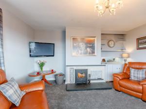a living room with two leather chairs and a fireplace at 3 Bed in Dumfries 77430 in Auldgirth