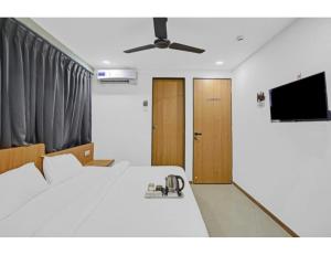 a bedroom with a white bed and a flat screen tv at Hotel Saarthi Inn, Surat in Surat