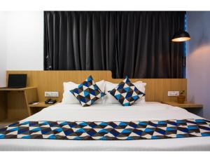 a bedroom with a large bed with blue and white pillows at Hotel Saarthi Inn, Surat in Surat