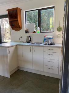 a white kitchen with a sink and a window at Jordan Place in Parua Bay