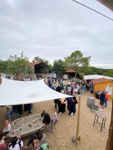 una multitud de personas sentadas alrededor de una tienda en un evento en Camping de la ferme au ânesses, mobil home happy, en Bressuire
