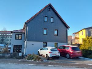 two cars parked in a parking lot in front of a house at Fewo Rosi in Brotterode