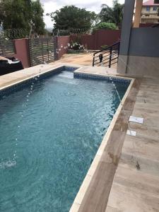 een zwembad met blauw water in een tuin bij Calm Hillside Swimming Pool Villa Apartment in Accra