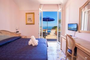 a bedroom with a bed and a view of the ocean at Hotel Terme Cristallo Palace & Beach in Ischia