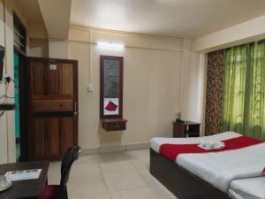 a bedroom with a bed and a table and a door at Balaji Guest House in Shillong