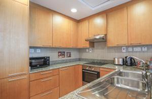 a kitchen with wooden cabinets and a stainless steel sink at Elite LUX Holiday Homes - Bay Square Luxury Studio in Business Bay Dubai in Dubai