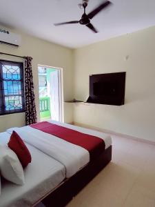 a bedroom with a bed and a flat screen tv at JV HOLIDAY HOME CANDOLIM in Candolim