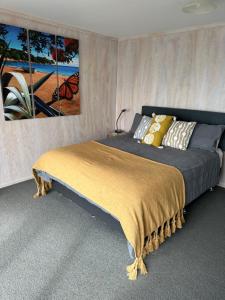a bedroom with a bed with a painting on the wall at Te Mata Bay Seaviews in Tapu