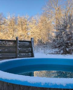 a snow covered bird bath with a bench in the background at Kylås Vildmark in Skillingaryd