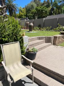 a chair sitting on a patio with some plants at Little fern self catering in George