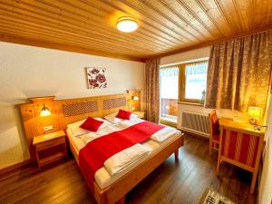 a bedroom with a large bed with a red blanket at Frühstückspension Seeblick in Achenkirch