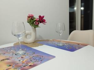 una mesa con dos copas de vino y un jarrón con flores en Love story en Iaşi
