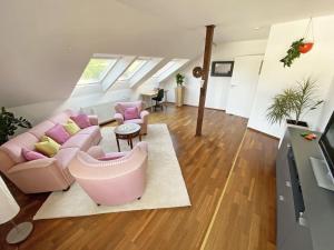 uma sala de estar com um sofá rosa e cadeiras em Ferien am Königshof em Georgsmarienhütte