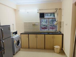 eine Küche mit einem Waschbecken, einer Waschmaschine und einem Fenster in der Unterkunft 1bhk Apartment in Saldhana Kyle Gardens, Calangute in Calangute