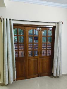 ein Paar Holztüren in einem Zimmer mit Vorhängen in der Unterkunft 1bhk Apartment in Saldhana Kyle Gardens, Calangute in Calangute