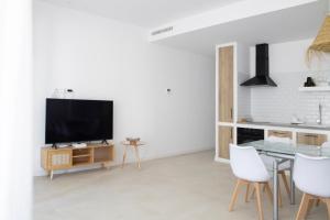 ein Wohnzimmer mit Fernseher und Tisch und Stühlen in der Unterkunft Nuevo apartamento planta baja in Bellreguart