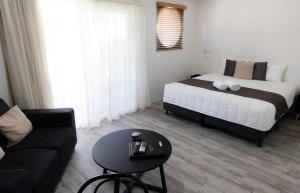 1 dormitorio con cama, sofá y mesa en Aston Hill Motor Lodge en Port Macquarie